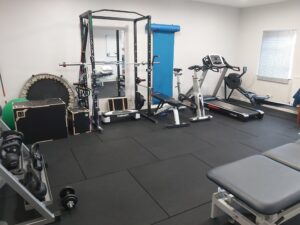 Rehabilitation gym based in Lisburn showing various equipment including a squat rack and treadmill